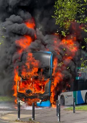 A double decker bus engulfed in flames 